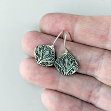 Load image into Gallery viewer, Silver earrings with intricate patterns held between fingers against a neutral background