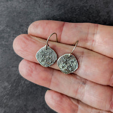 Load image into Gallery viewer, Silver earrings with an intricate design held between fingers against a dark gray background
