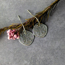 Load image into Gallery viewer, Silver diamond-shaped earrings on a gray surface with pink flowers and green leaves.
