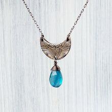 Load image into Gallery viewer, Necklace with a crescent moon pendant and blue teardrop bead on a light wooden background

