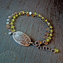 Load image into Gallery viewer, Bracelet with green beads and a decorative leaf charm on a textured surface

