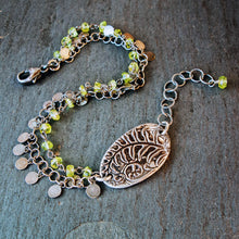 Load image into Gallery viewer, Bracelet with leaf charm and green beads on a textured surface
