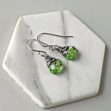 Load image into Gallery viewer, Green earrings with silver wire wrapping on a hexagonal stone surface
