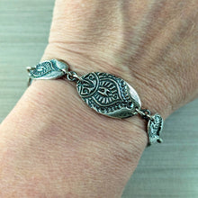 Load image into Gallery viewer, Silver bracelet with leaf designs on a wrist against a neutral background
