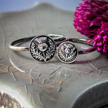 Load image into Gallery viewer, Silver rings with intricate designs, one larger, one smaller, on a textured surface with pink flowers.
