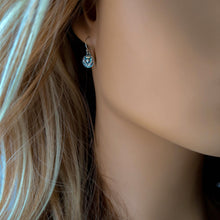 Load image into Gallery viewer, Close-up of a person wearing a round silver earring with an embossed thistle design
