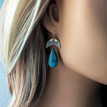 Load image into Gallery viewer, Close-up of a person wearing a blue teardrop earring with intricate silver design.
