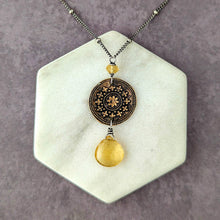Load image into Gallery viewer, Necklace with a decorative pendant with a yellow stone drop on a hexagonal stone stand against a gray background
