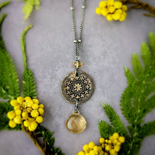 Load image into Gallery viewer, Necklace with decorative pendant on a gray background with yellow flowers and green leaves.
