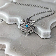 Load image into Gallery viewer, Necklace with a decorative pendant featuring a blue gemstone on a textured surface

