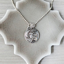 Load image into Gallery viewer, Silver necklace with a pendant on a textured ceramic surface
