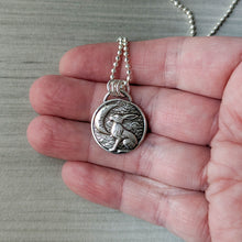 Load image into Gallery viewer, Silver pendant with a rabbit design held in a hand against a neutral background
