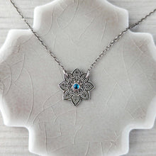Load image into Gallery viewer, Silver necklace with a star-shaped pendant on a textured surface
