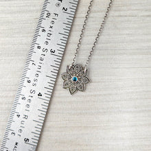 Load image into Gallery viewer, Silver necklace with a floral pendant next to a ruler on a textured surface
