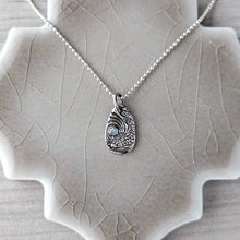 Load image into Gallery viewer, Silver necklace with a detailed pendant on a ceramic tile stand.
