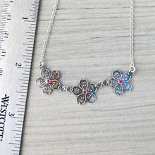 Load image into Gallery viewer, Floral necklace with colorful stones on a gray surface next to a ruler.
