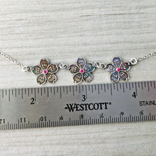 Load image into Gallery viewer, Silver floral necklace with pink gemstones above a ruler for size reference

