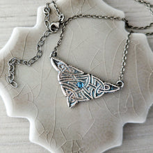 Load image into Gallery viewer, Silver necklace with a decorative pendant and blue gemstone on a textured surface
