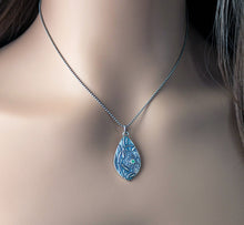 Load image into Gallery viewer, A teardrop shaped silver pendant with a green faceted stone hanging on a silver chain worn by a mannequin
