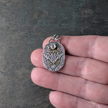 Load image into Gallery viewer, A silver necklace with an intricately designed pendant depicting a flying bat with a pale gray stone held in a hand to show size
