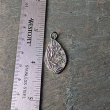 Load image into Gallery viewer, A teardrop shaped silver pendant with a green faceted stone lying next to a ruler for size arranged on a gray slate tile
