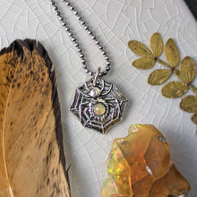 Load image into Gallery viewer, A silver spider with a smooth opal stone set into the abdomen laying flat on a white crackle glazed tile with natural props
