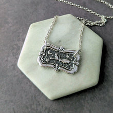 Load image into Gallery viewer, Silver necklace with a decorative pendant on a white stone surface
