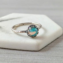 Load image into Gallery viewer, Silver ring with an opal in an intricate frame on a white stone surface
