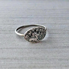Load image into Gallery viewer, Silver ring with embossed design on a gray textured background
