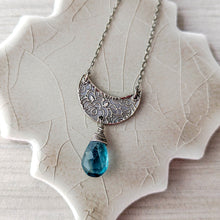 Load image into Gallery viewer, Back detail of silver crescent moon pendant with blue teardrop gemstone on a textured beige surface
