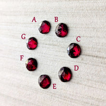 Load image into Gallery viewer, Rose cut garnet cabochons labeled A to G on a textured white background
