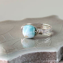 Load image into Gallery viewer, Silver ring with a turquoise blue larimar stone on a textured surface

