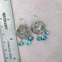 Load image into Gallery viewer, Silver earrings with blue gemstones on a neutral background with a ruler for scale.
