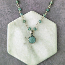 Load image into Gallery viewer, Necklace with a blue pendant and beads and pendant on a hexagonal stone surface
