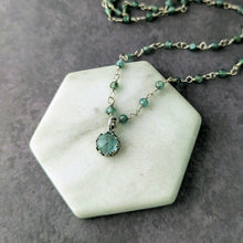 Load image into Gallery viewer, A blue pendant and beads necklace on a hexagonal stone with a gray background
