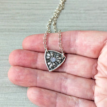 Load image into Gallery viewer, Silver necklace with a shield-shaped pendant held in a hand for scale
